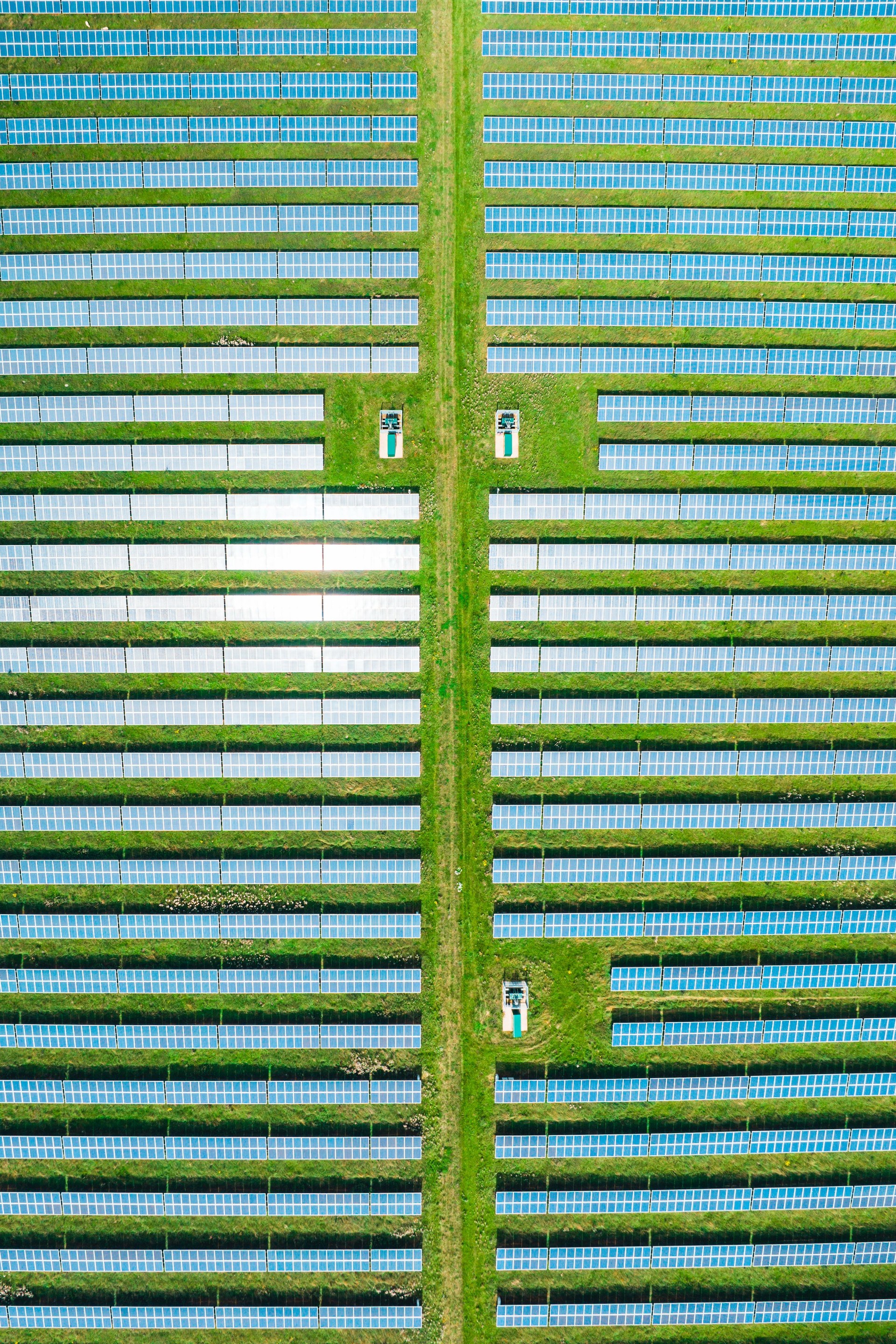 Aerial view of solar panels on green field at suburb in sunny day